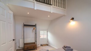 A bedroom with a bunk bed, a bed with striped bedding, a radiator, a window, and a wall-mounted light fixture. - Spring Rose (Bedale)
