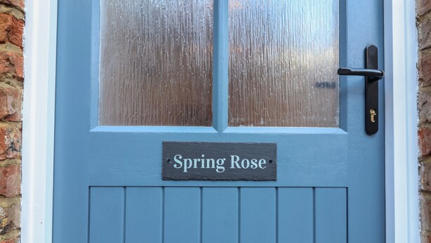 A blue door with a frosted glass panel and a sign reading "Spring Rose". - Spring Rose (Bedale)