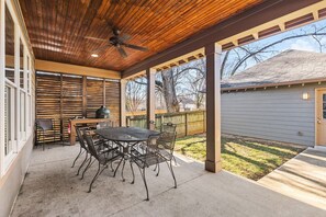 A covered patio with a table and chairs, a ceiling fan, and a view of a backyard.
