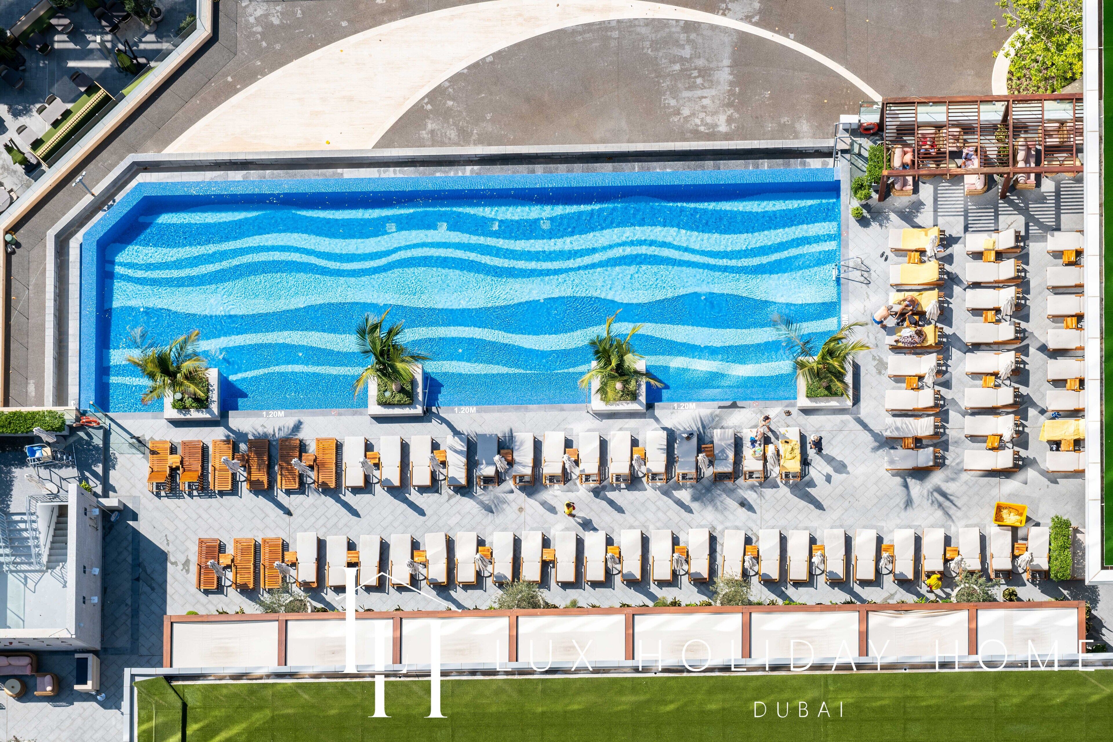 Une piscine sur le toit, avec un motif ondulatoire, entourée de chaises longues et de palmiers.