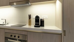 A modern kitchen with wooden cabinets, a stainless steel range hood, a built-in oven, a coffee machine, and a knife block. - LUX  Iconic Views at Palm Tower Studio 2 (Dubai)