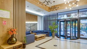 Eine moderne Lobby mit einem blauen Sofa, einem Holzbüro, einer Marmorwand und einer Drehschleuse.