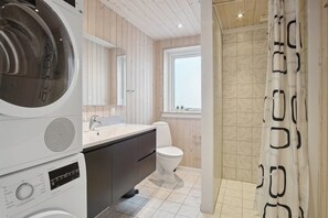 Ein modernes Badezimmer mit Waschmaschine, Waschbecken, Toilette und Dusche.