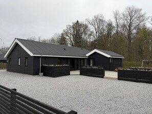 A modern black building with a sloped roof and a gravel driveway.