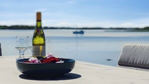 A table with a bottle of wine, glasses, and a bowl with flowers. - Lovely beach house with panoramic view (Martofte)