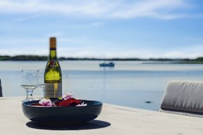 Une table avec une bouteille de vin, des verres et un vase rempli de fleurs.