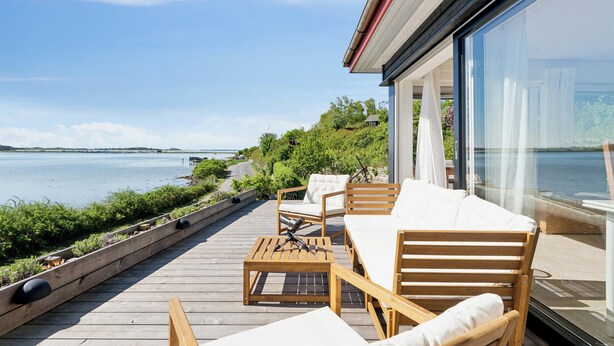 A deck with outdoor furniture overlooking a body of water. - Lovely beach house with panoramic view (Martofte)