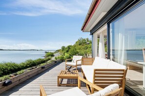 A deck with outdoor furniture overlooking a body of water.