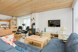 Ein gemütliches Wohnzimmer mit einer Couch, einem Holztisch, einem Fernseher, einem Kamin und einem Essbereich.
