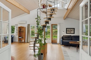 Un vaste espace de vie agrémenté d’un escalier en colimaçon, d’un canapé, d’une table basse et d’une grande fenêtre donnant sur l’extérieur.