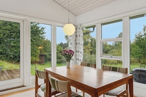 Een eetgedeelte met een houten tafel, stoelen en een bloevas.