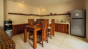Una cocina con armarios de madera, un refrigerador de acero inoxidable, una cafetera y una mesa de comedor con sillas.