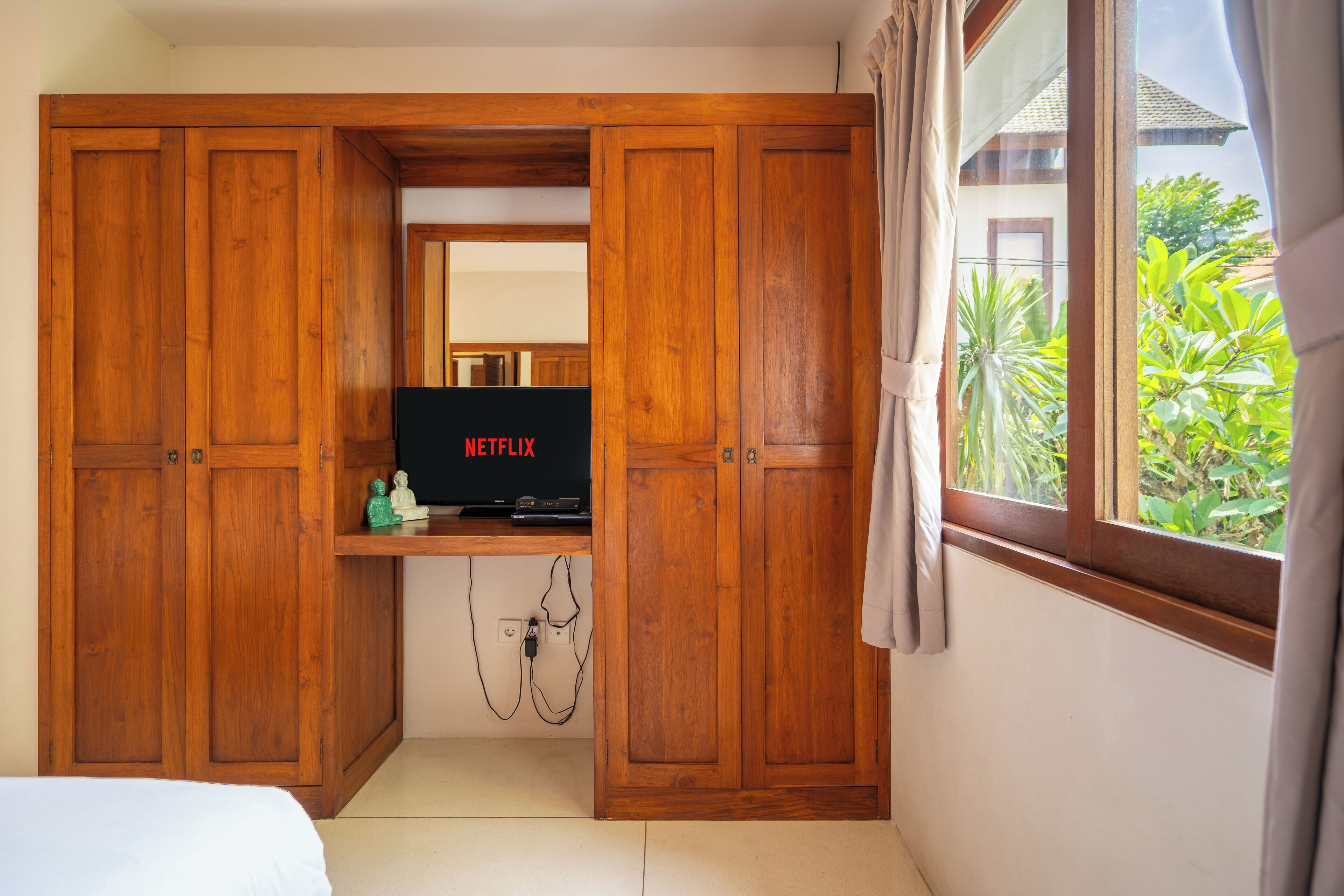Un dormitorio con armarios de madera, un televisor en un estante y una ventana con cortinas.