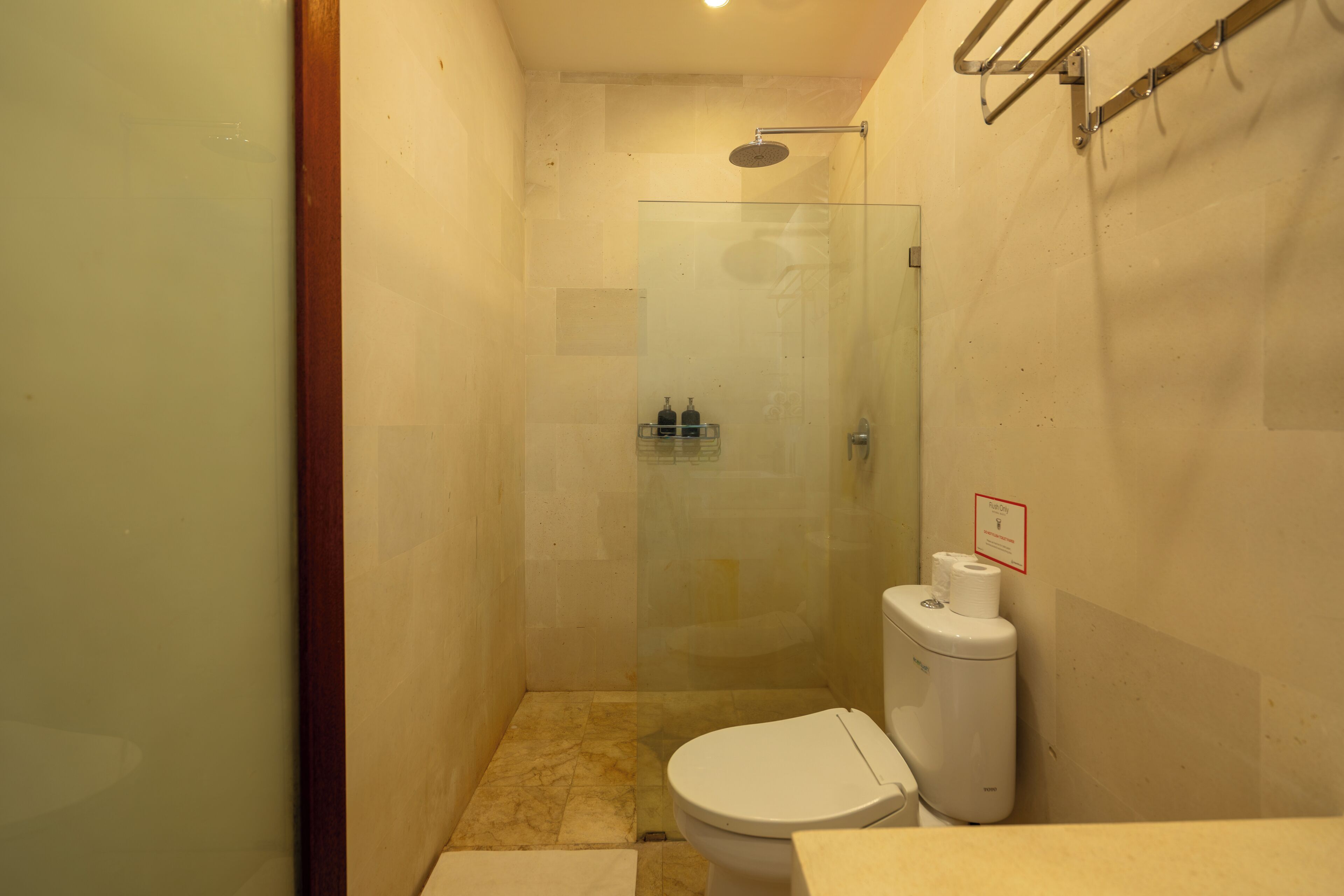 A small bathroom with a glass shower enclosure, a toilet, and a sink.