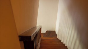 Una escalera de madera con una pared blanca a un lado y una cortina blanca al otro.