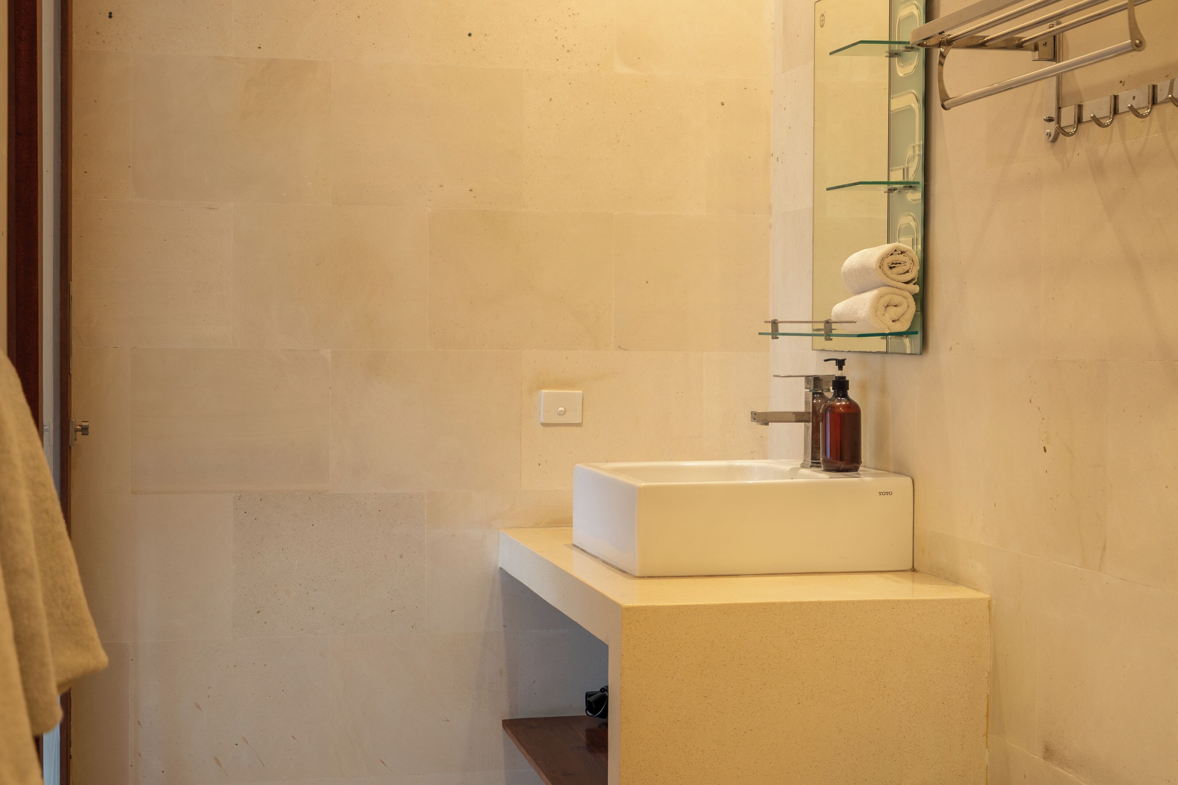 A bathroom with a white sink, a mirror, and a towel rack with towels.