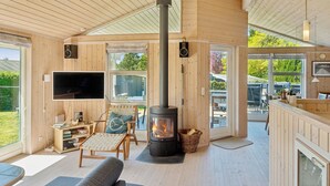 Een houten interieur met een open haard, een flatscreen televisie en een eethoek.