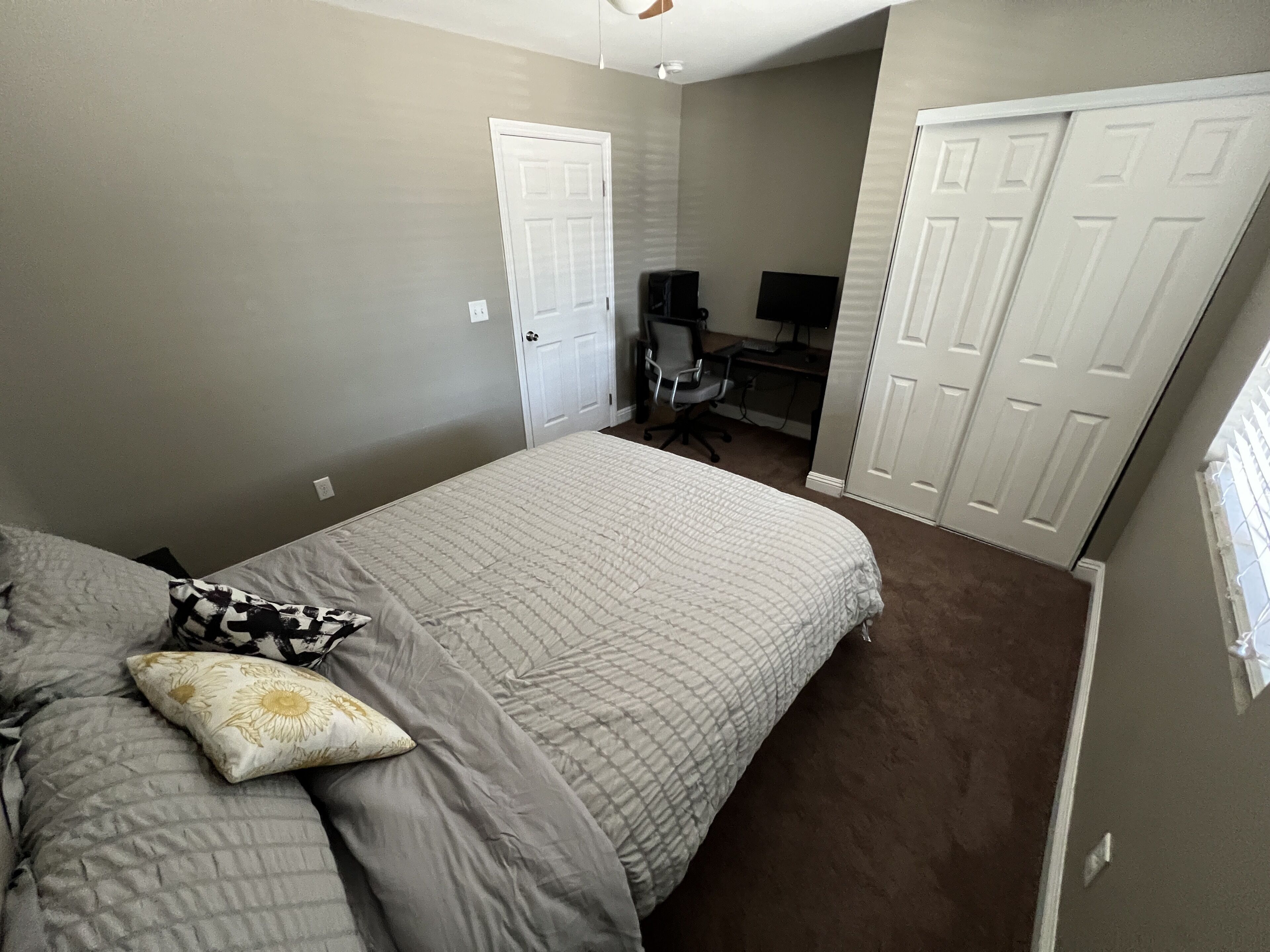 A bedroom with a bed, a desk, and two doors.