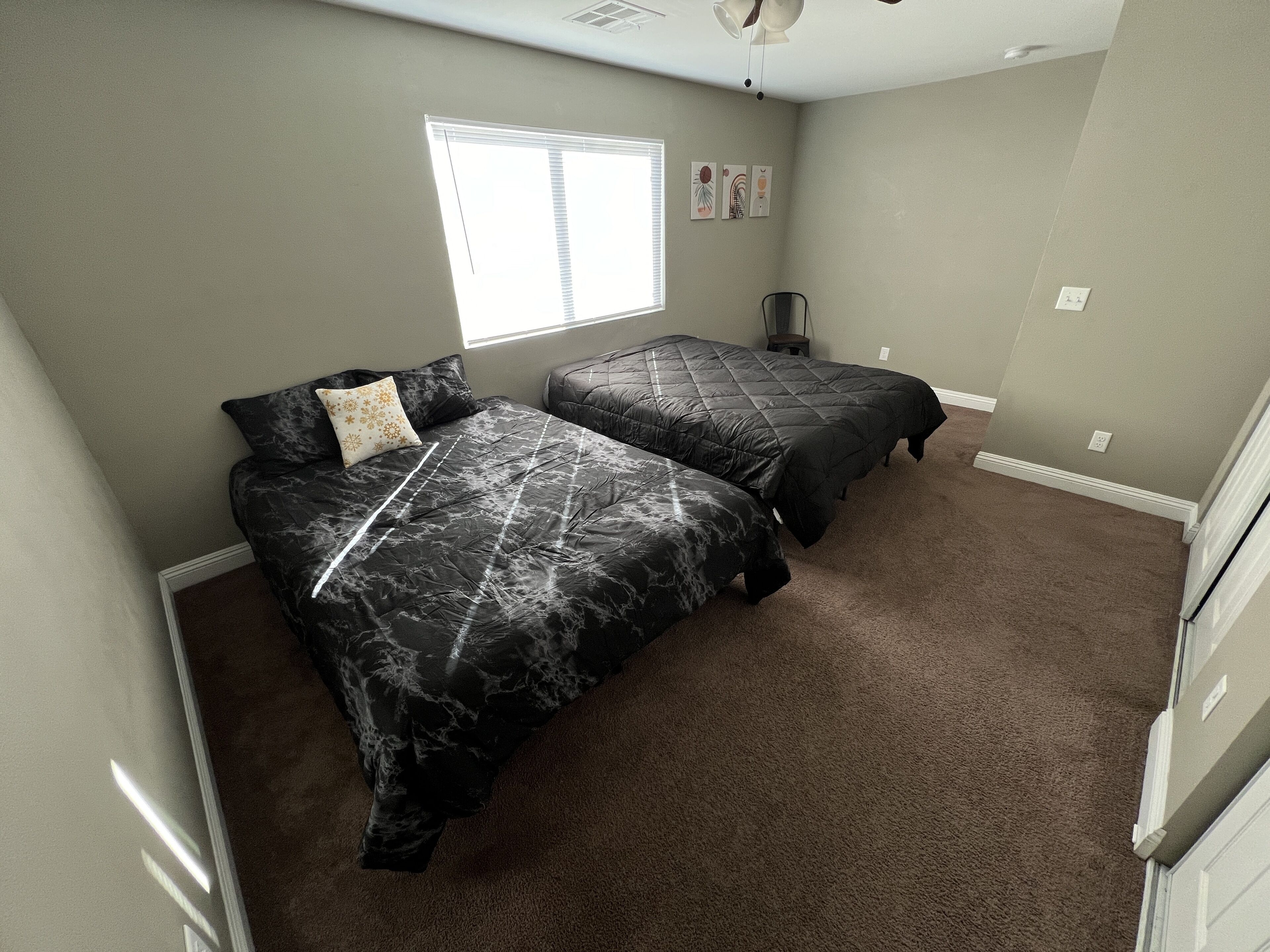A bedroom with two beds, a window, and a ceiling fan.