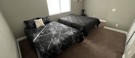 A bedroom with two beds, a window, and a ceiling fan.