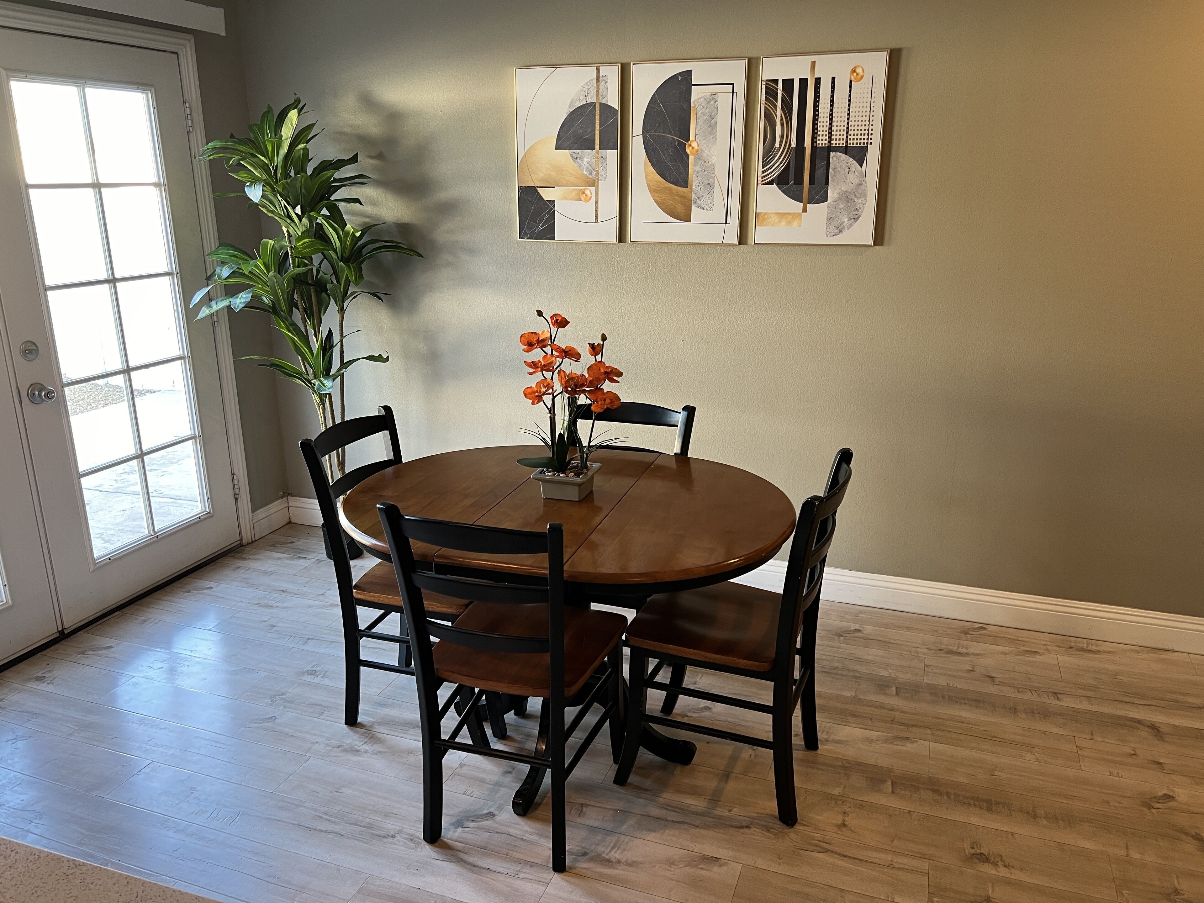 A dining area with a round wooden table, four chairs, and a potted plant.
