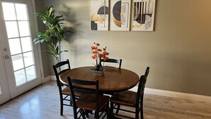 A dining area with a round wooden table, four chairs, and a potted plant.