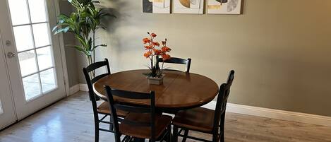 A dining area with a round wooden table, four chairs, and a potted plant.