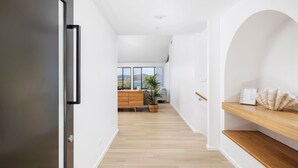 A modern interior with a wooden floor, white walls, a wooden cabinet, and a view through large windows.