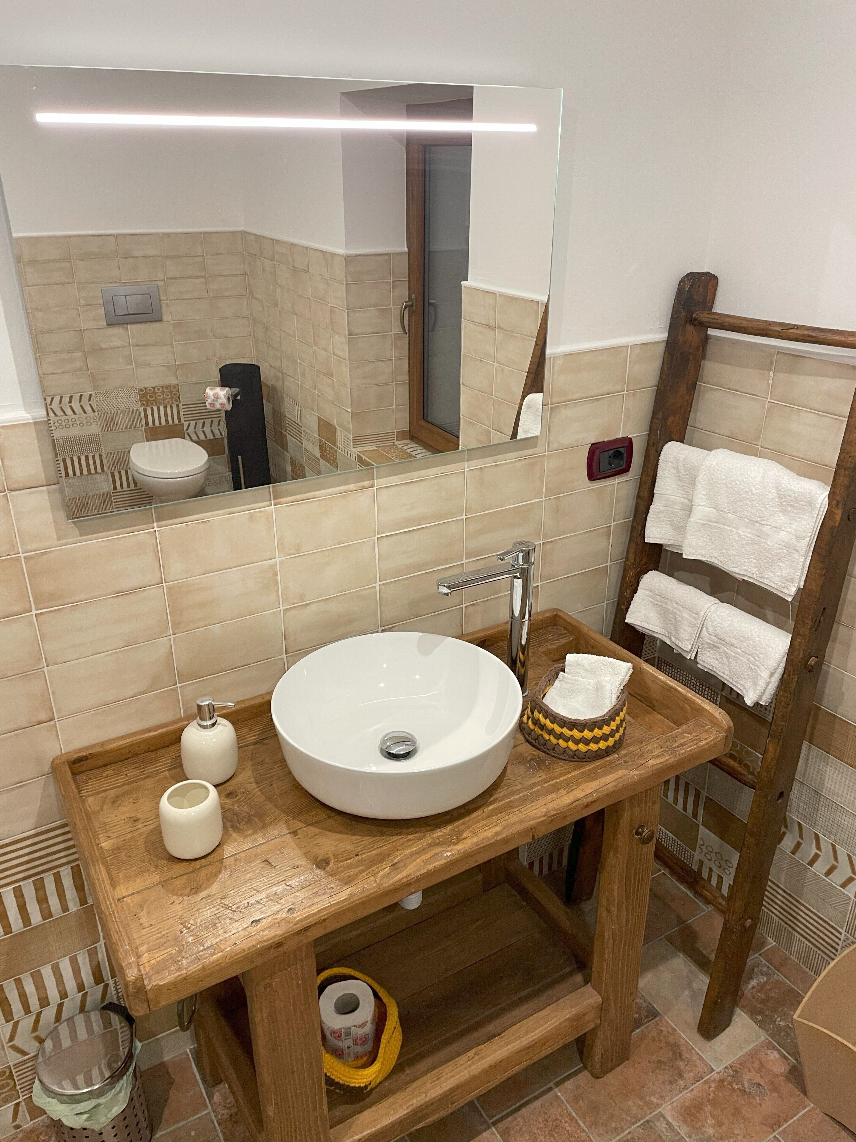 Un baño con un lavamanos blanco, tocador de madera y un espejo.