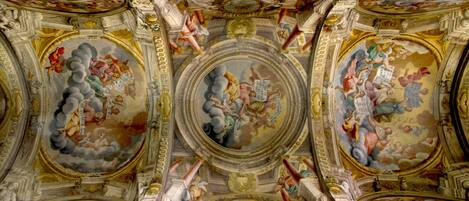 A grand hall with ornate ceiling frescoes and classical architectural elements.