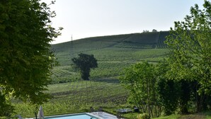 Ein Poolbereich mit Liegestühlen und einer Pergola, umgeben von üppiger Vegetation und Hügeln.