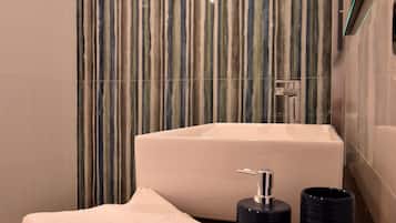Ein modernes Badezimmer mit einer großen Badewanne, einer Duschkabine aus Glas und einer hölzernen Sitzbank mit Handtuch.
