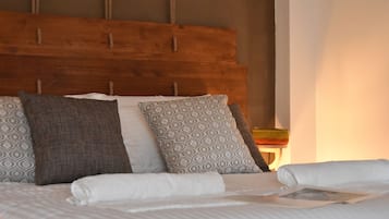 Una cama bien hecha con almohadas estampadas y un cabecero de madera.