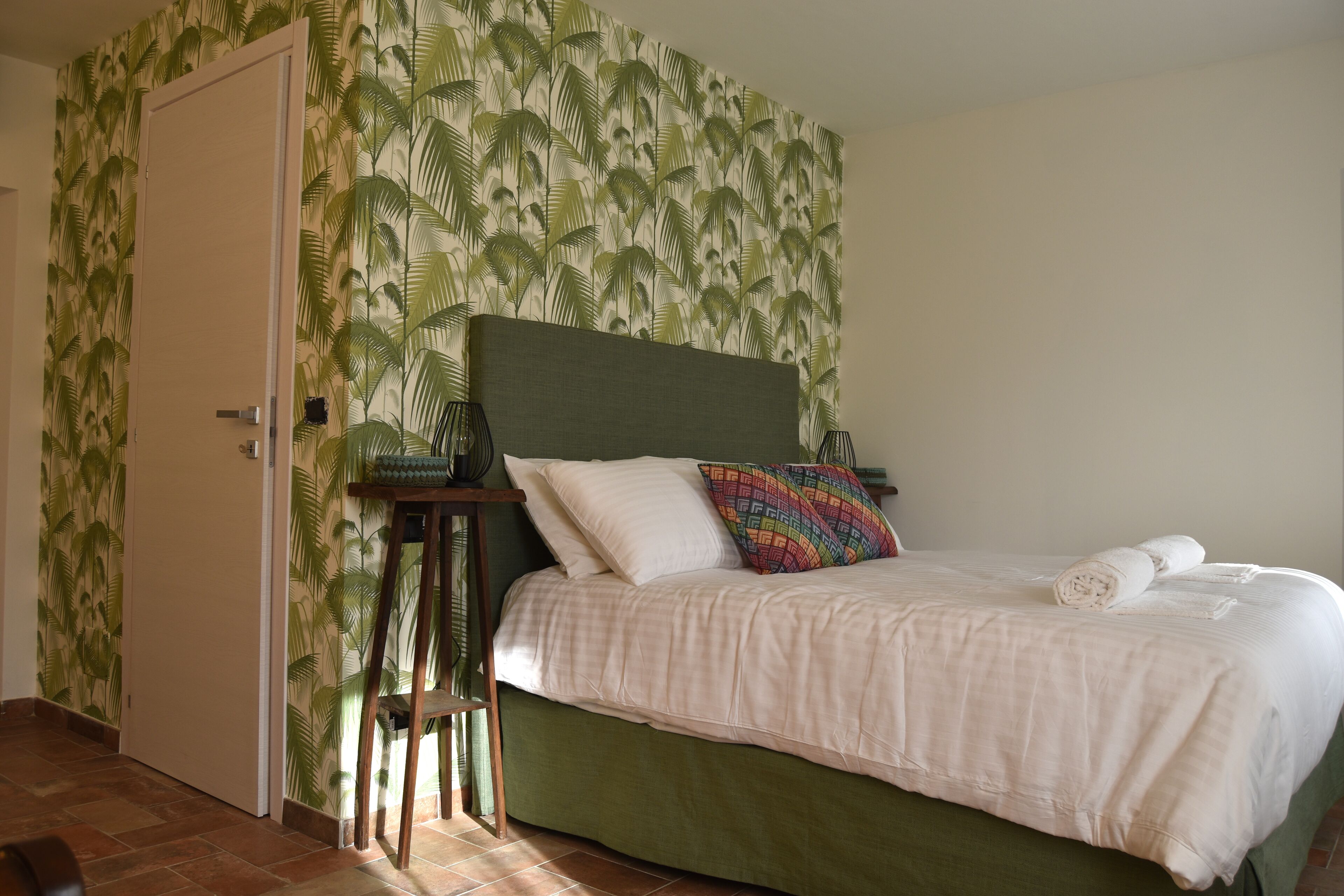 A bedroom with a bed, a nightstand, a chair, and a door.