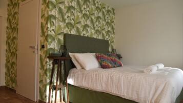 A bedroom with a bed, a nightstand, a chair, and a door.