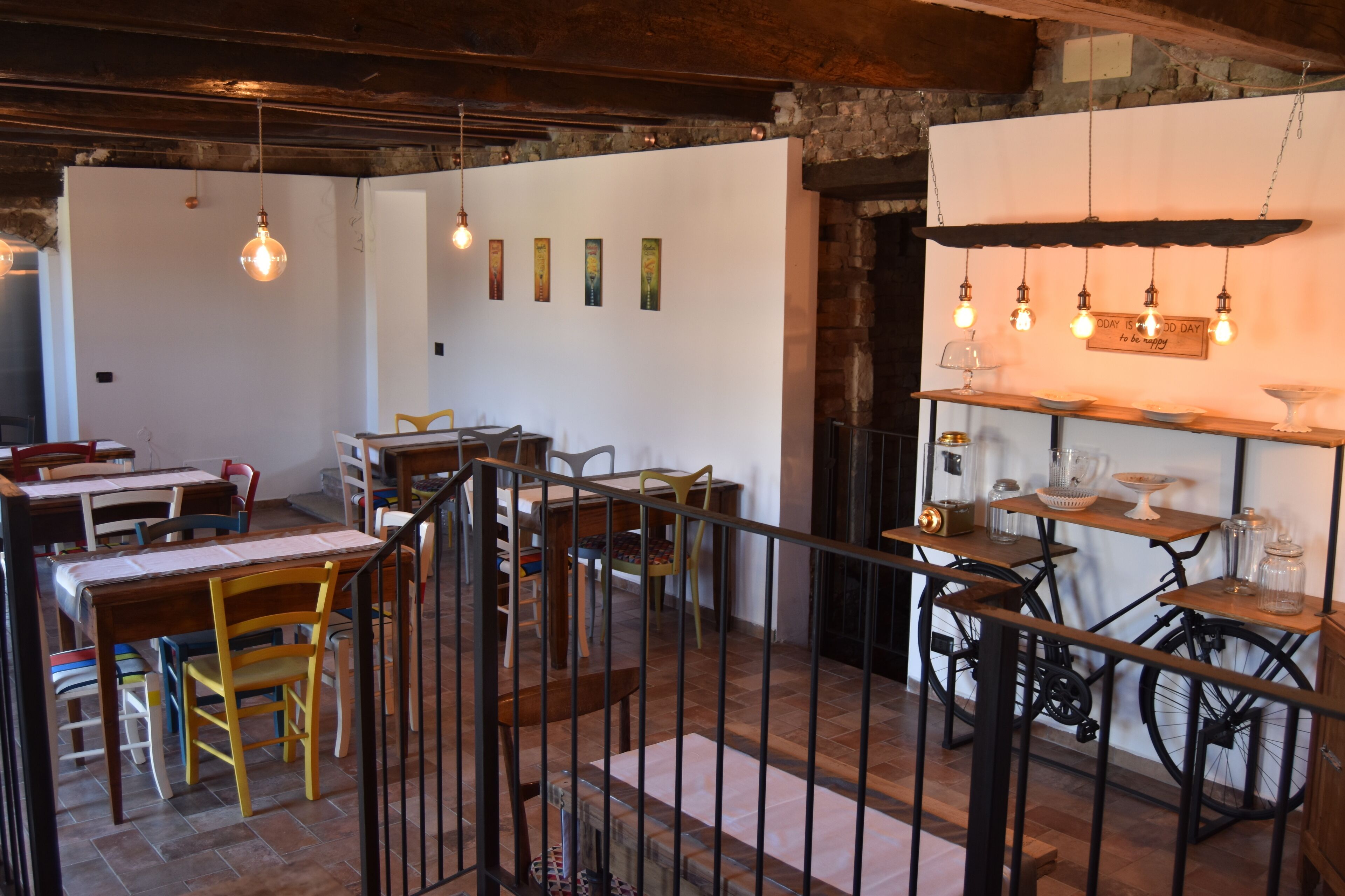 Un interior rústico con mesas y sillas de madera, una bicicleta y una estantería con frascos.