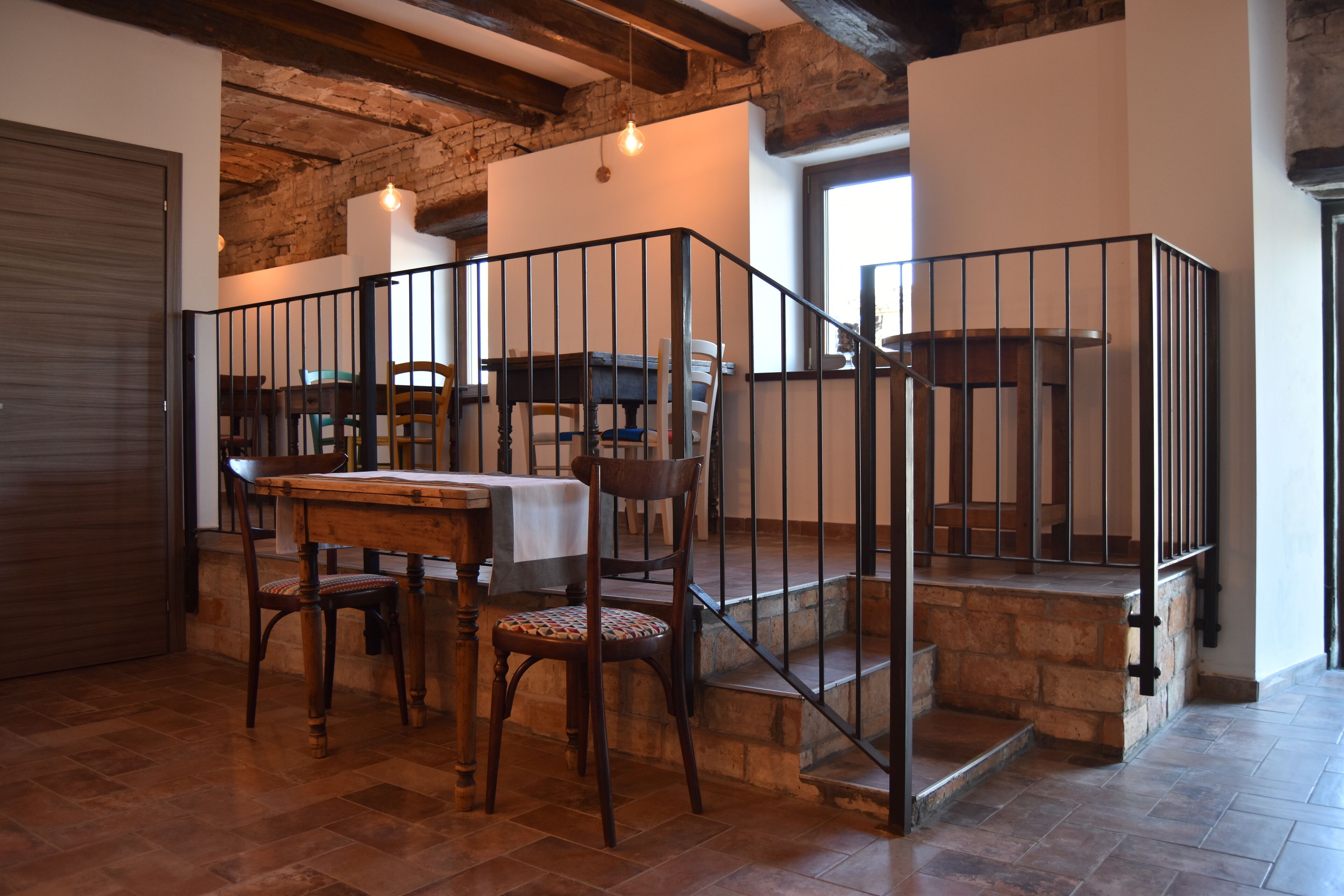 Un comedor con una mesa y sillas de madera, una escalera con escalones de piedra y una pared de ladrillo.