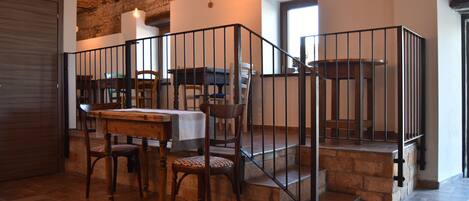 Uma sala de jantar com mesa e cadeiras de madeira, escadas de pedra e uma parede de tijolos.