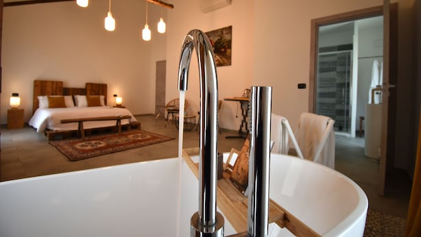 Ein modernes Badezimmer mit einer großen weißen Badewanne, einem Holzwaschtisch und einer hängenden Leuchte.