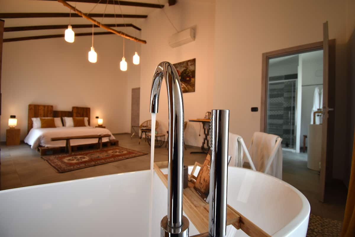 Une salle de bain moderne avec une grande baignoire blanche, un meuble-lavabo en bois et un luminaire suspendu.