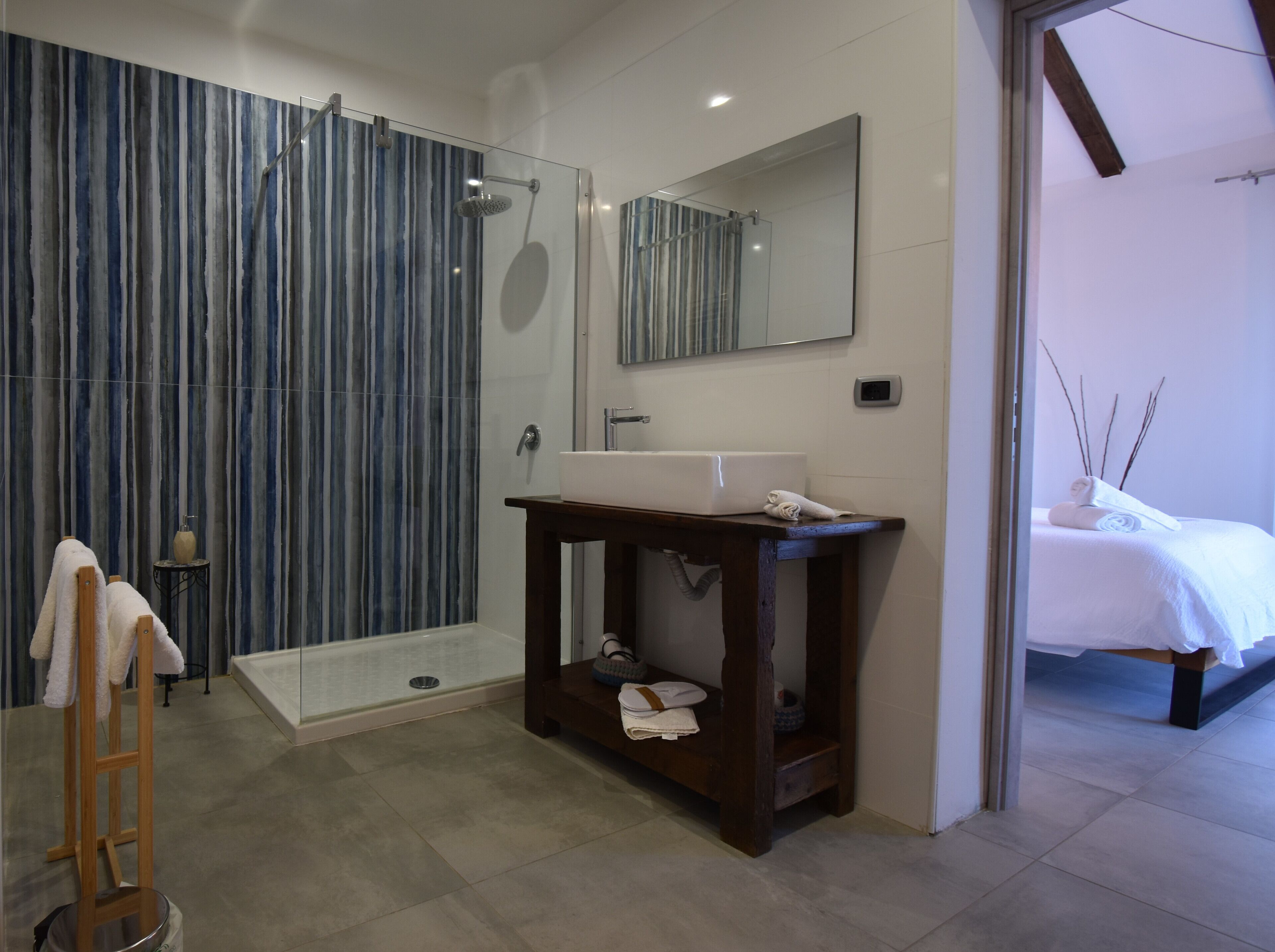 Ein modernes Badezimmer mit Glasdusche, einem Holzkosmetikschrank und einem großen Spiegel.