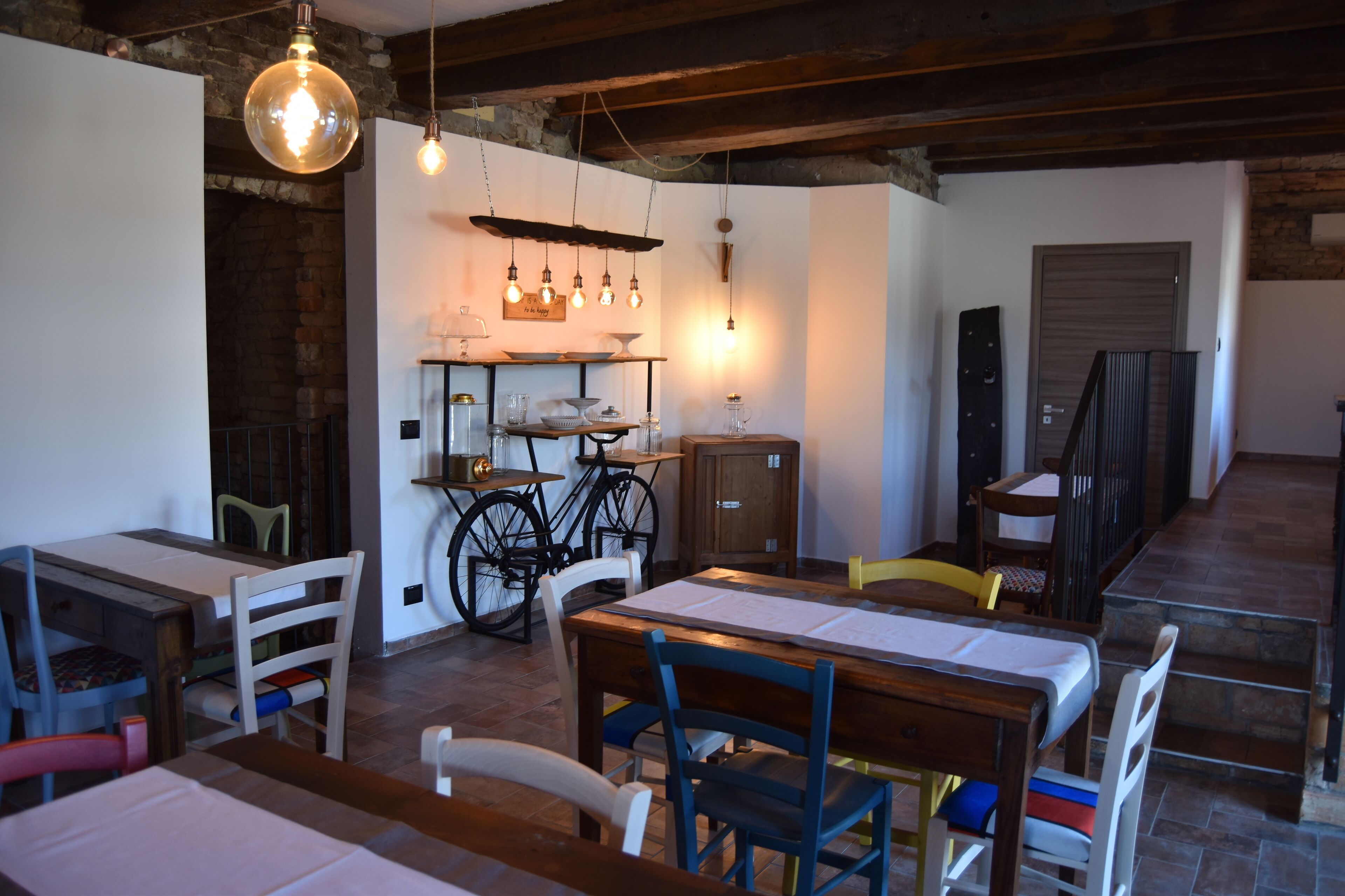A dining area with wooden tables and chairs, a brick wall, and hanging light fixtures.