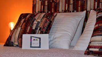Una cama bien hecha con un cojín estampado y uno blanco, un letrero con el texto 'DIRECTORY' y 'USER INFORMATION', y una estantería llena de libros al fondo.