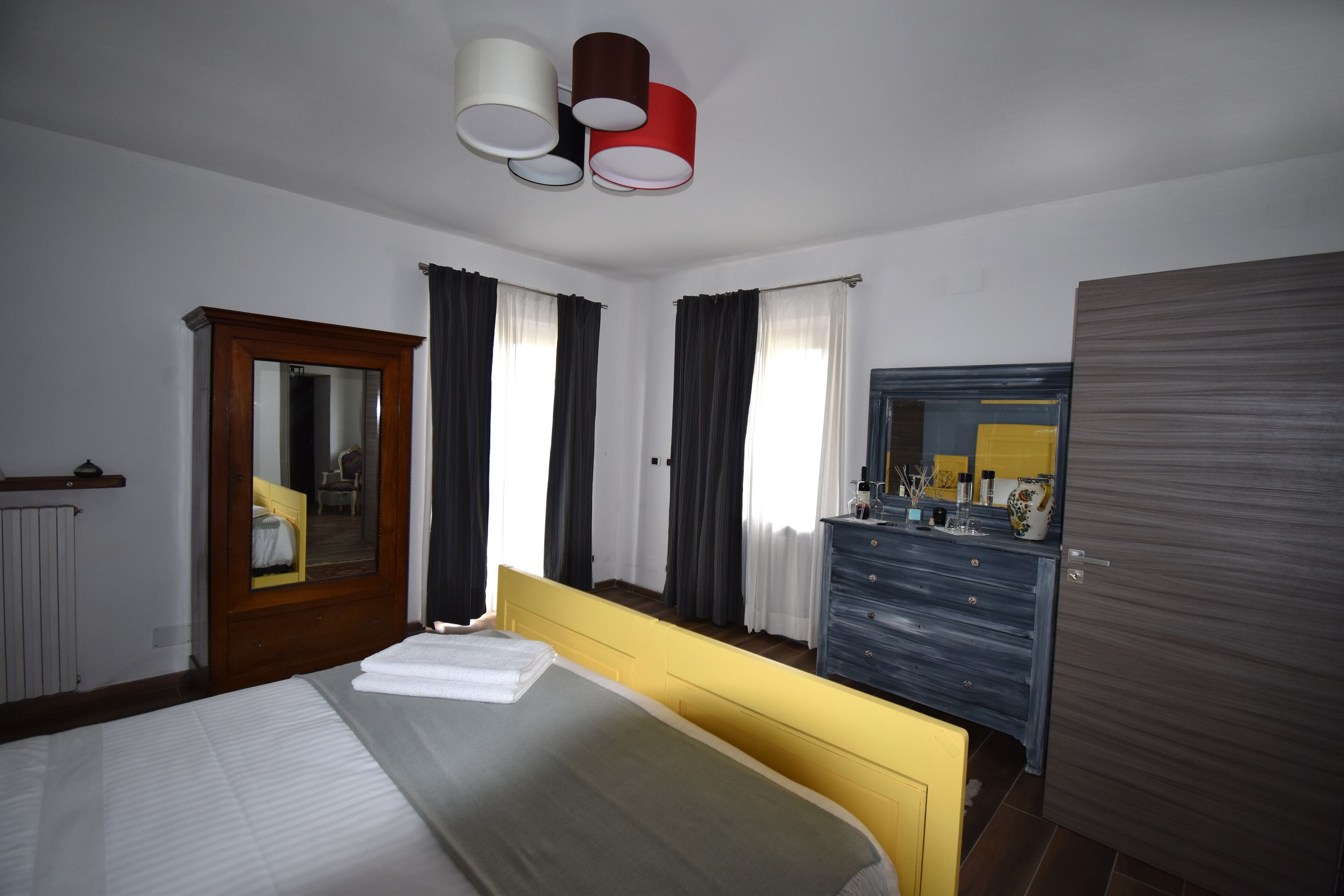 Een hotelkamer met een bed, een dressoir, een spiegel en een deur.