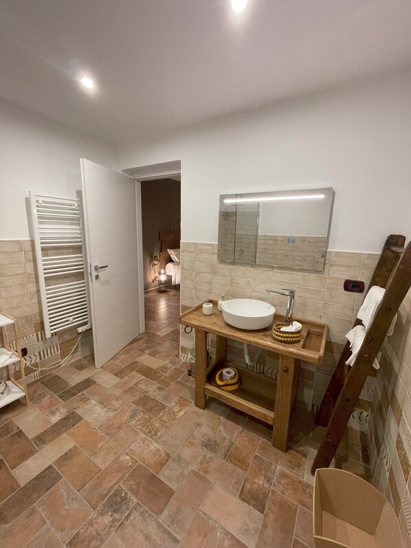 A bathroom with a large sink, a mirror, and a towel rack. - Cascina Tre Botti (Agliano Terme)