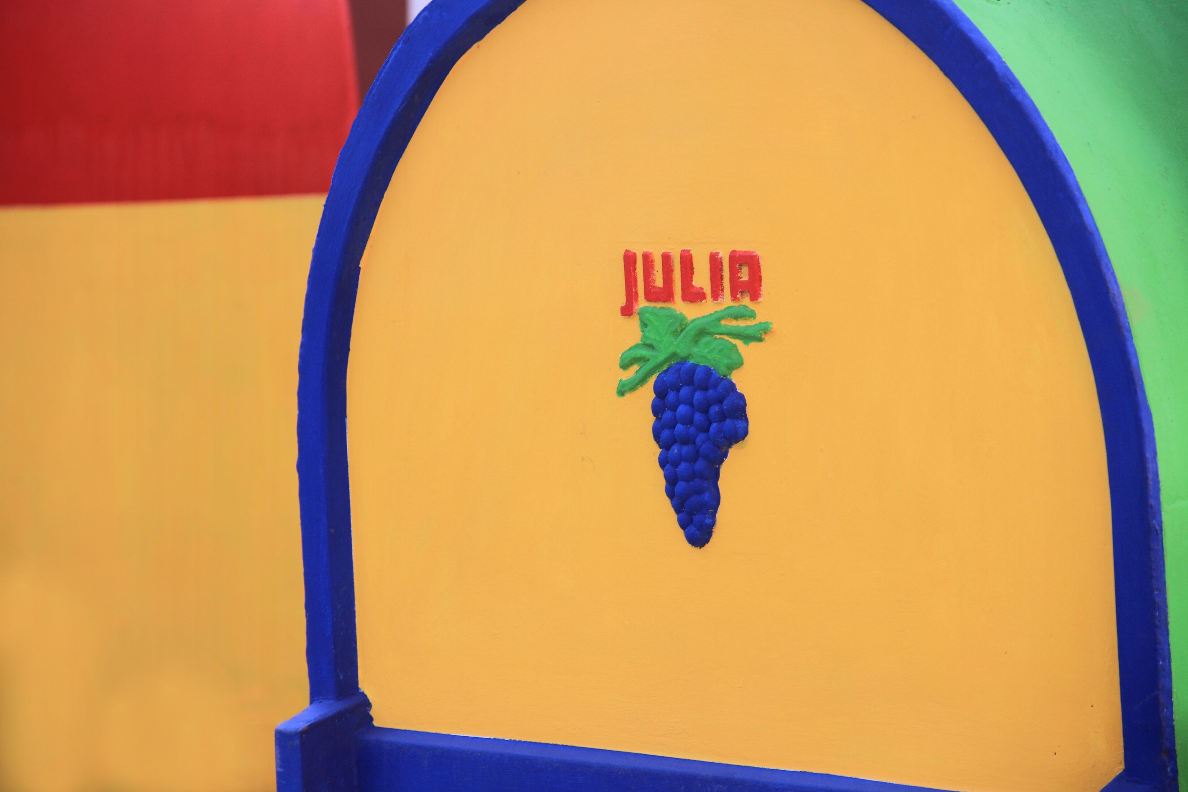 Un mur aux couleurs vives, surmonté d’une arche bleue et portant le nom « JULIA » en lettres rouges.