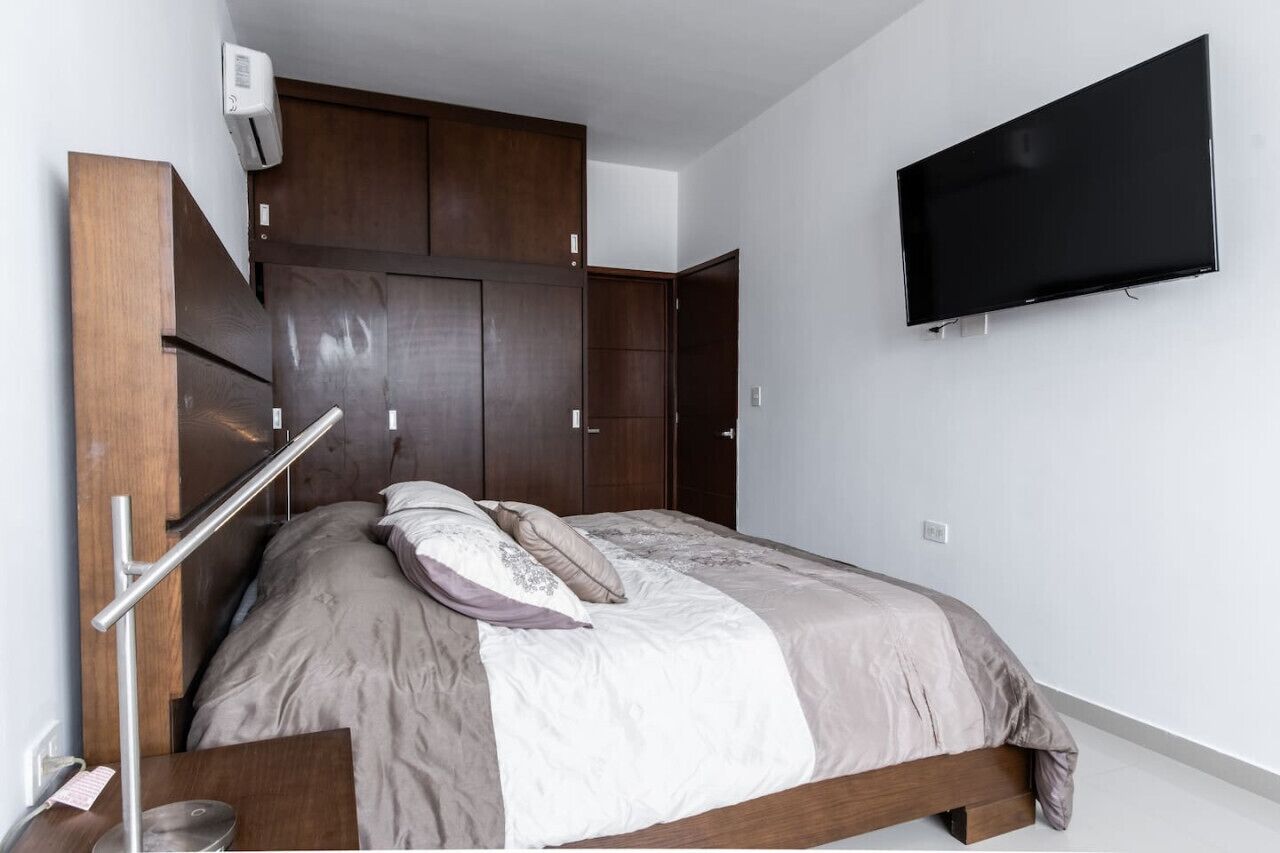 Ein modernes Schlafzimmer mit Bett, Einbauschrank und Wandfernseher.
