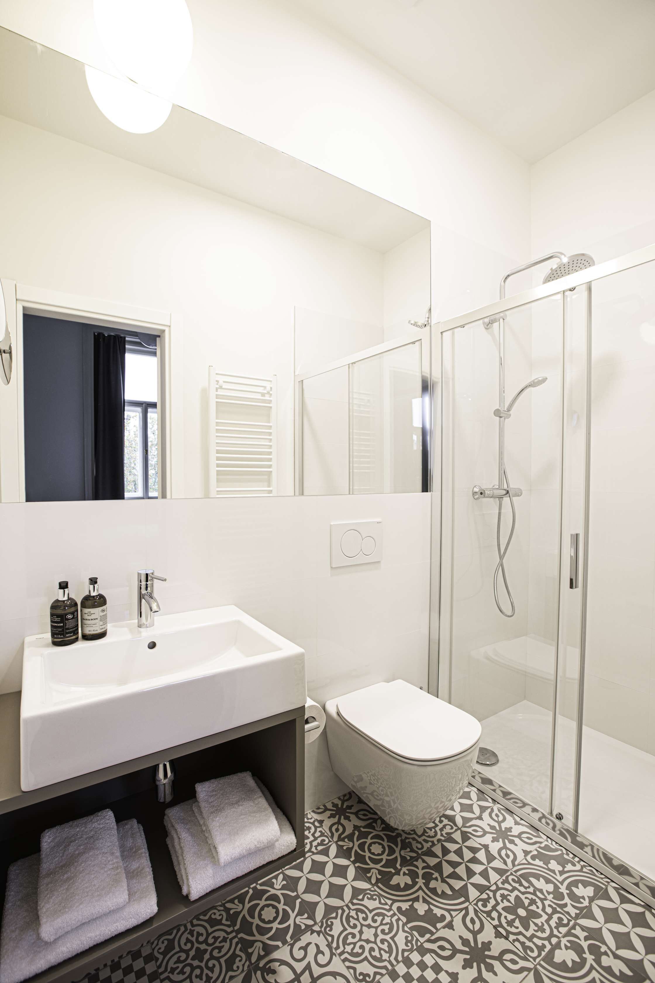 A modern bathroom with a glass-enclosed shower, a white sink, and a toilet.