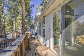 A wooden deck with a glass door leading to a room, surrounded by trees.