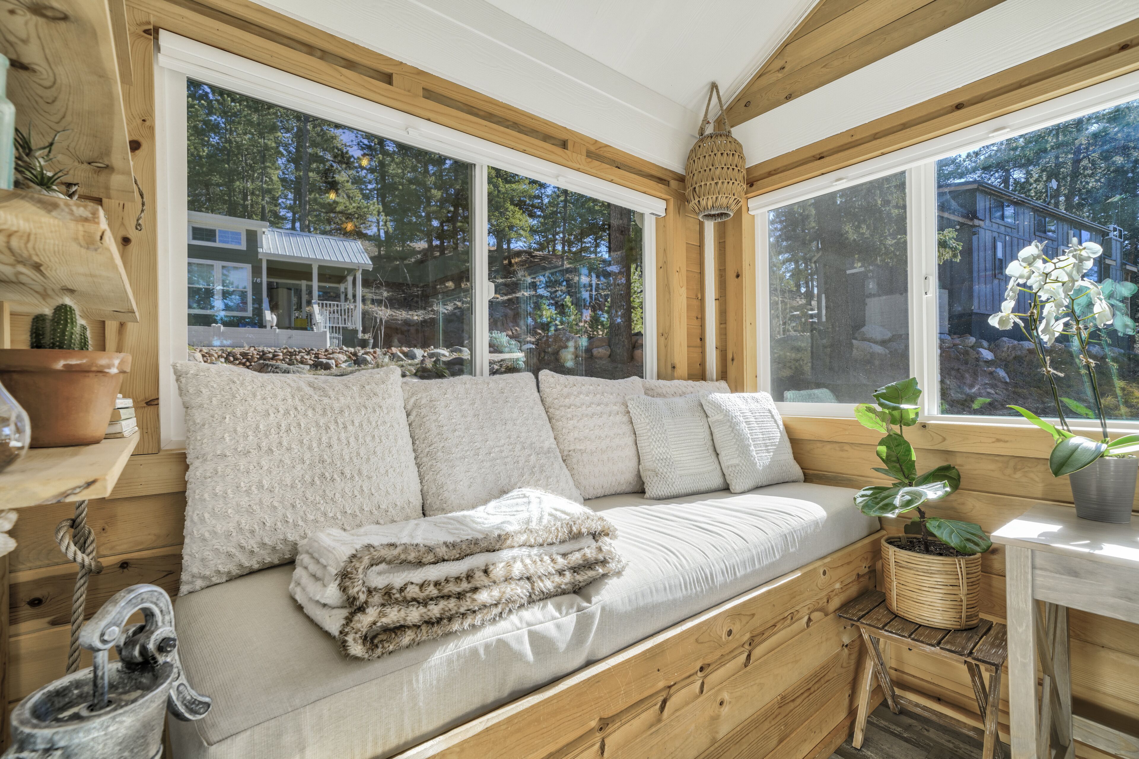 A cozy wooden cabin with a large window, a cushioned bench, and a rustic interior.